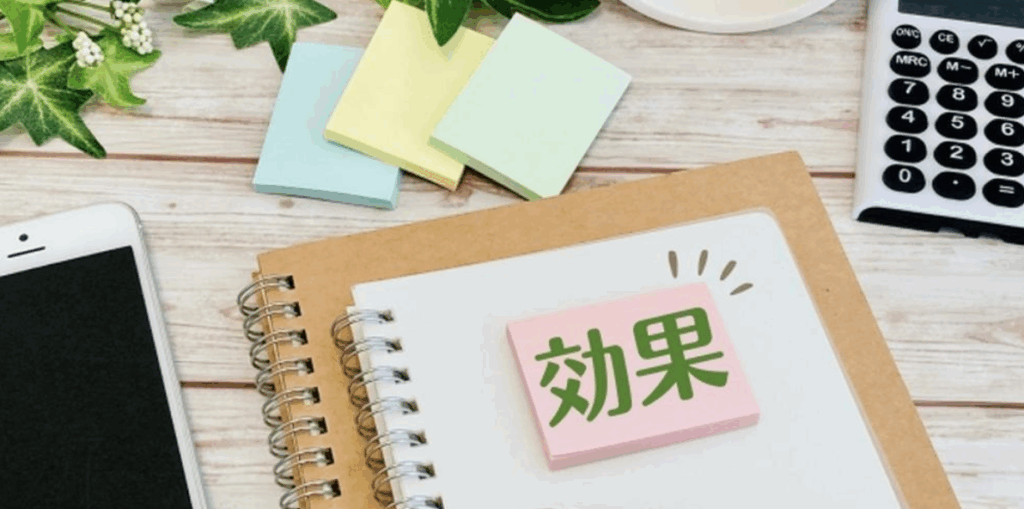 効果の文字が書かれたメモとノート、スマートフォンや電卓が置かれたデスクのイメージ