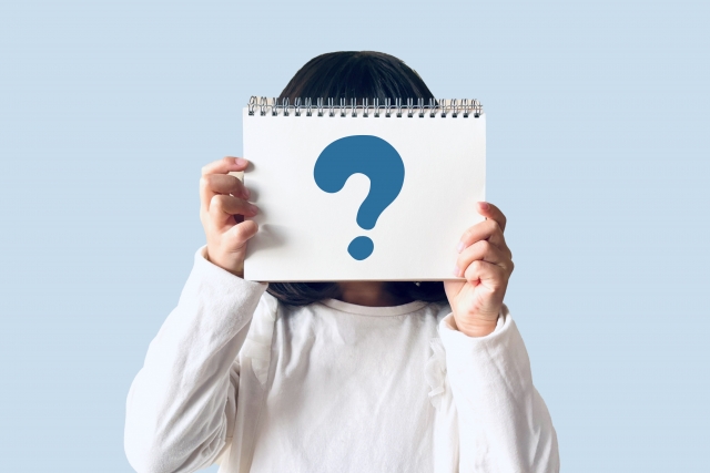 ハテナが描かれたノートを持つ子供